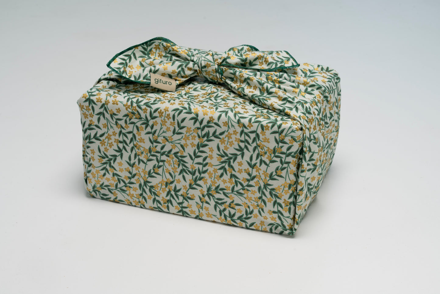 Geschenk verpackt mit dem Geschenktuch Lenz – grün mit goldenen Blumen im Furoshiki-Stil