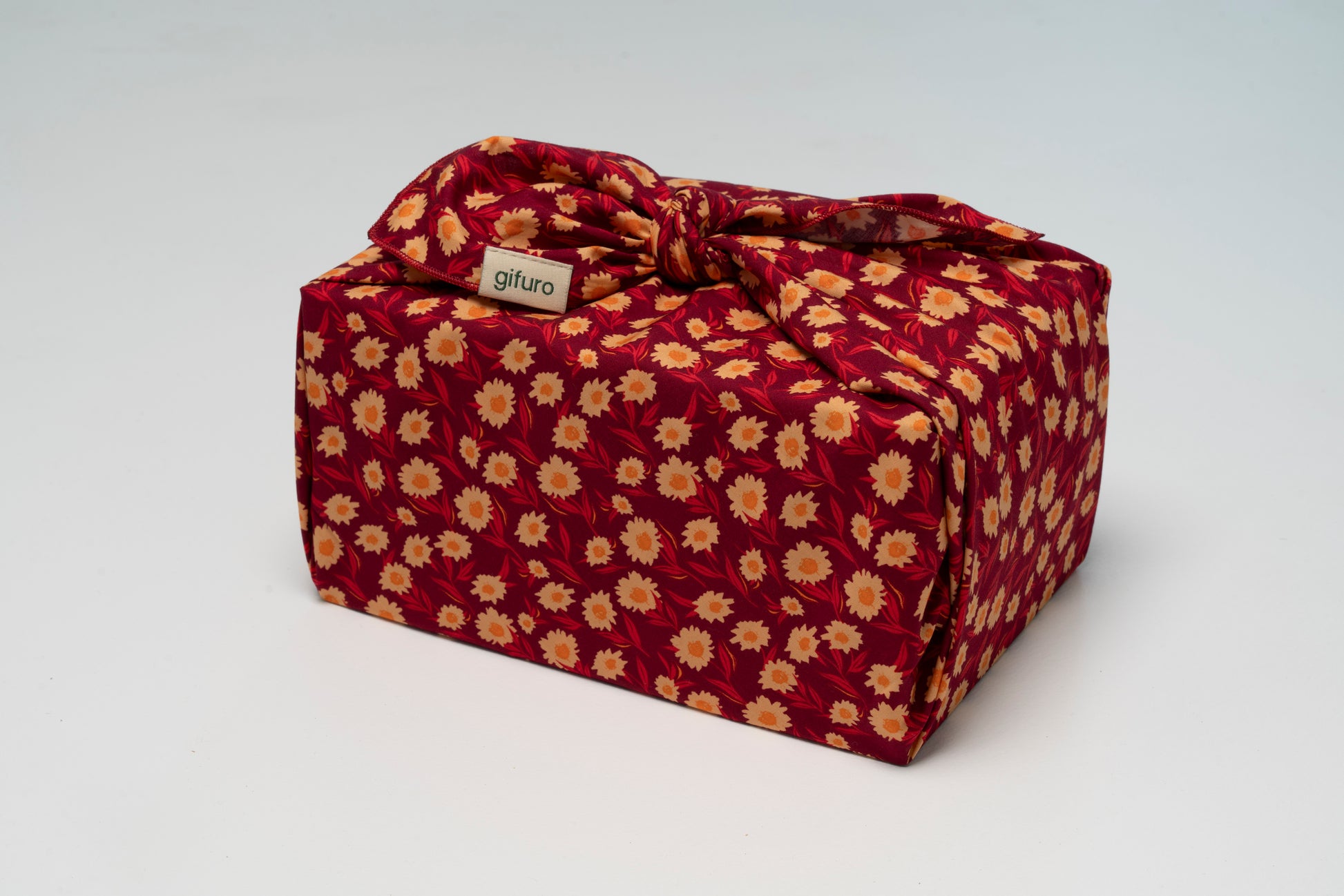 Geschenk verpackt mit dem Geschenktuch Aviva – rot mit floralem Muster im Furoshiki-Stil
