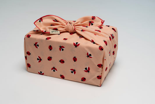 Geschenk verpackt mit dem Geschenktuch Bodo – hell mit Marienkäfer-Motiv im Furoshiki-Stil