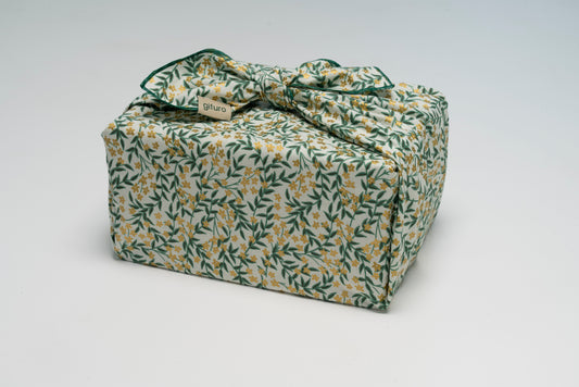 Geschenk verpackt mit dem Geschenktuch Lenz – grün mit goldenen Blumen im Furoshiki-Stil